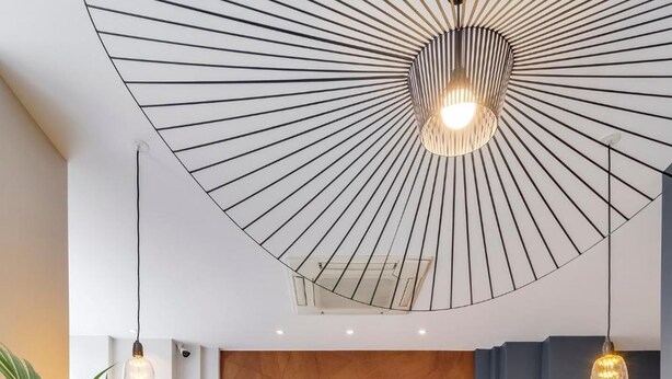 Een moderne woonkamer met een houten wandpaneel, een bank en twee fauteuils.
