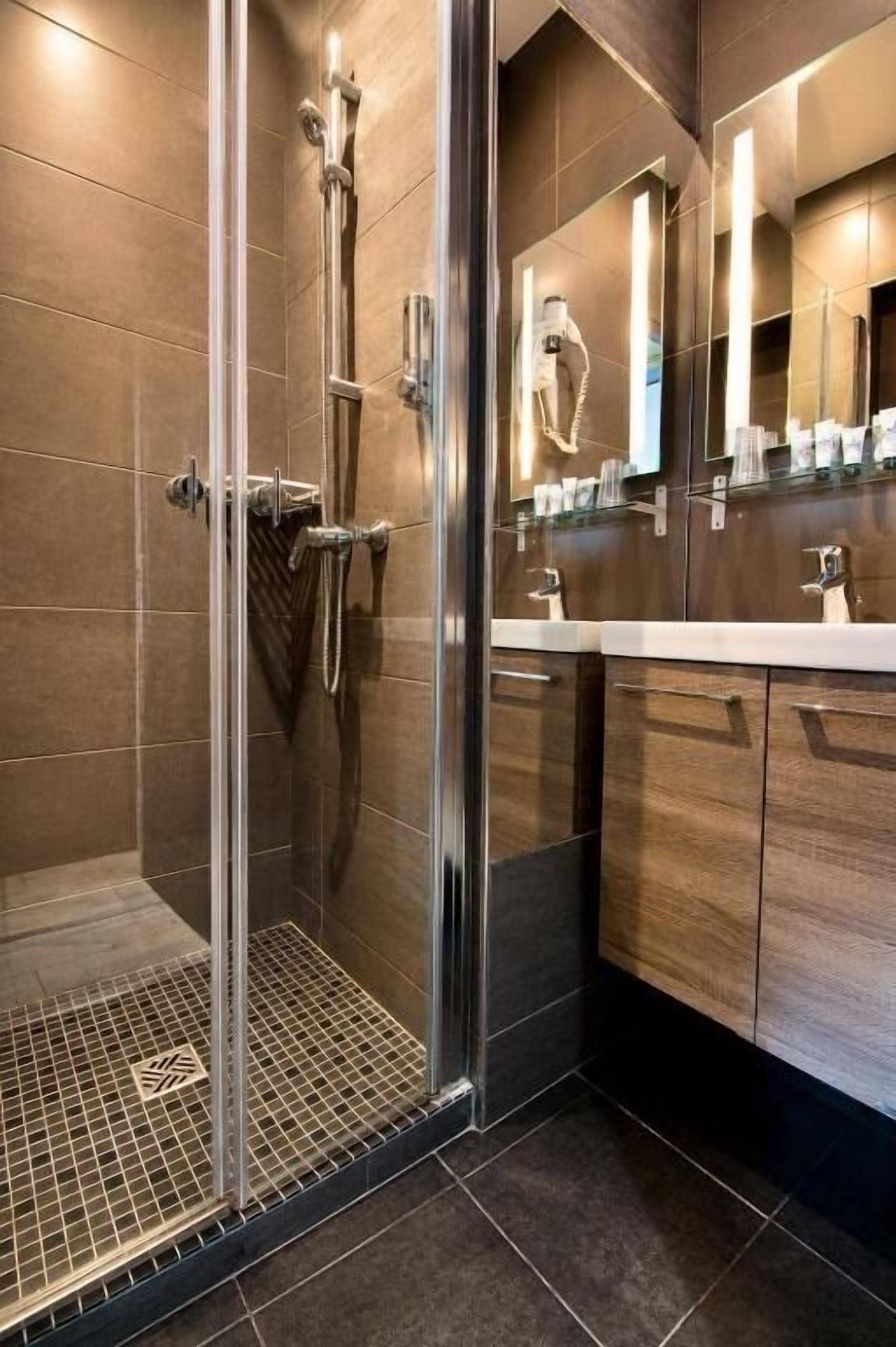 A modern bathroom with a glass shower enclosure, a vanity with a mirror, and a tiled floor.