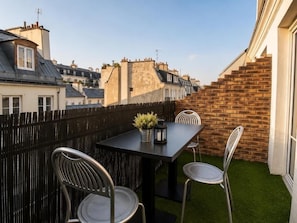 A terrace with a table and chairs, a potted plant, and a brick wall. - Hotel Migny Opera Montmartre (Paris)