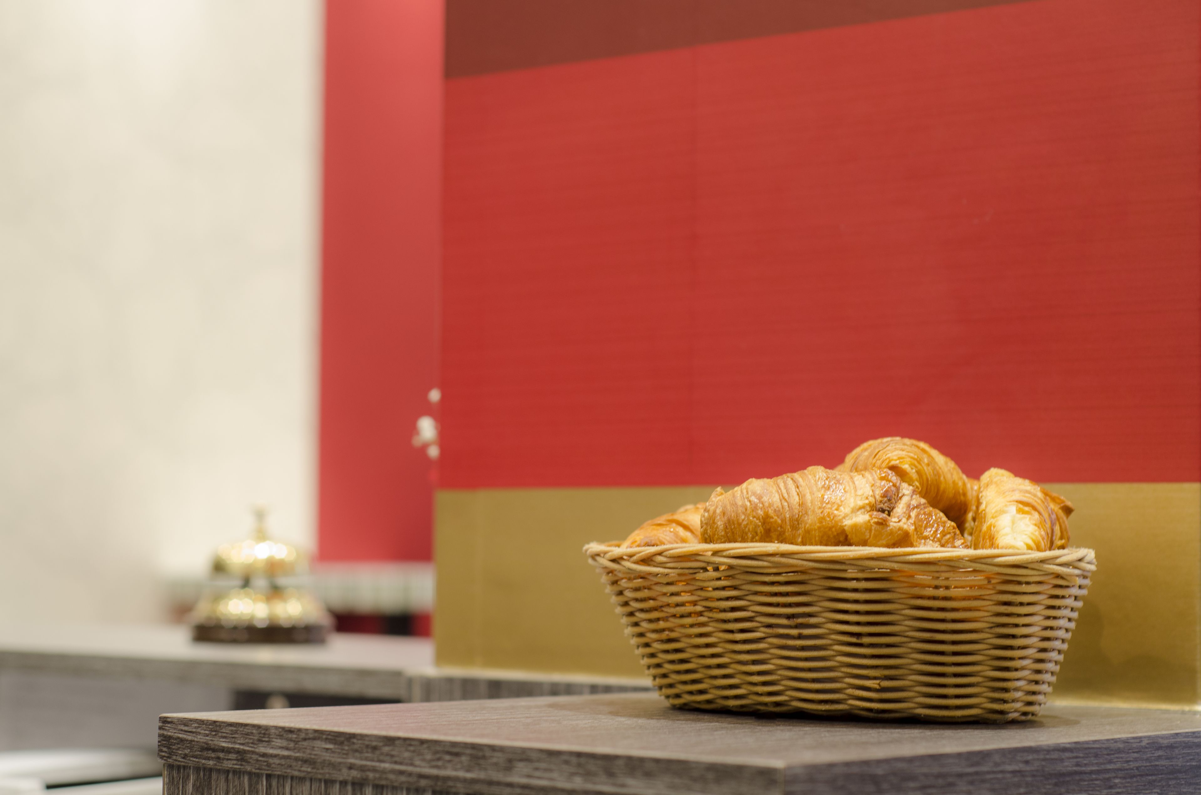 Een rieten mand met croissants op een marmeren aanrecht.