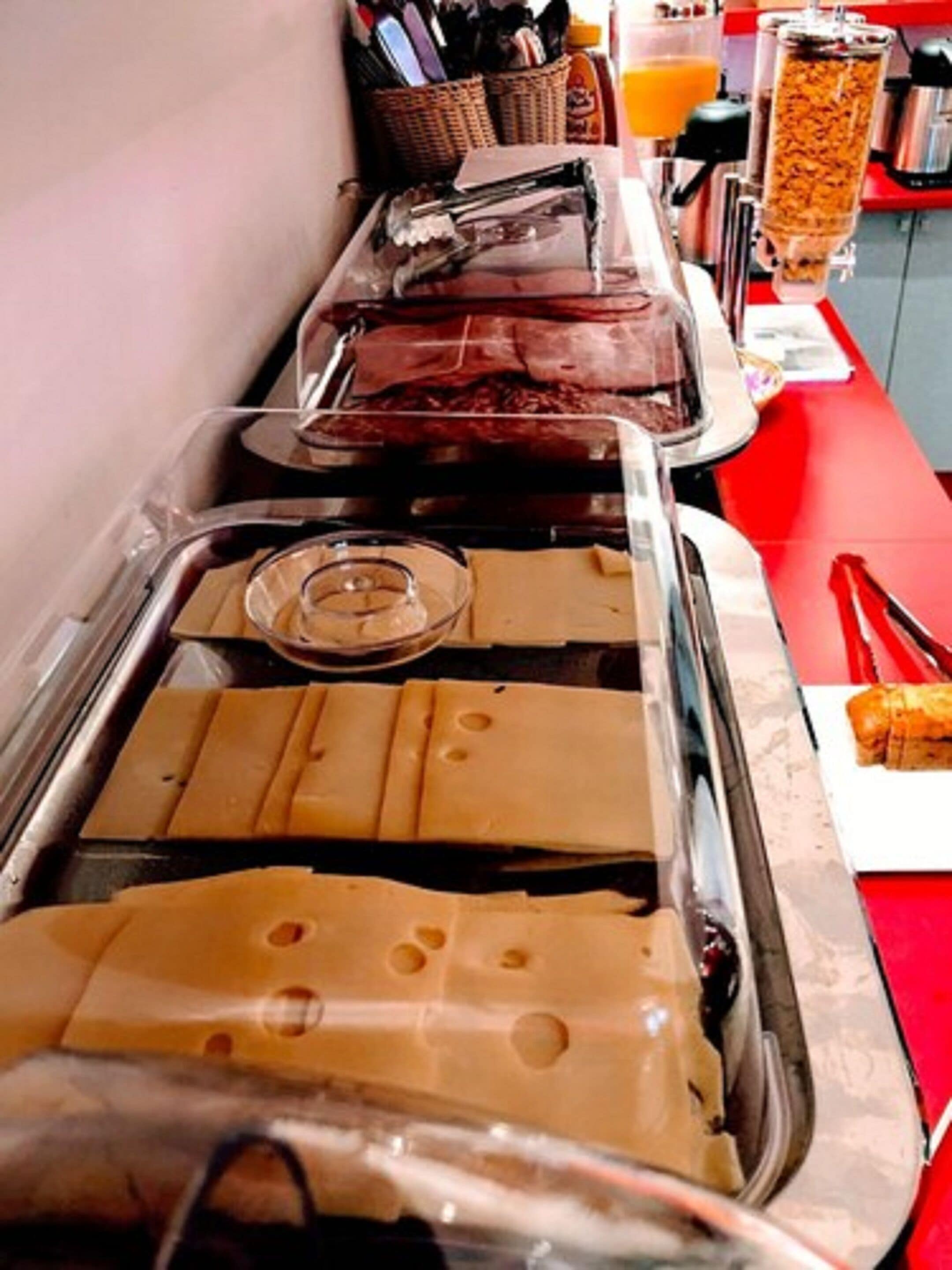 Un buffet con diversi cibi, tra cui panini e un erogatore di bevande.