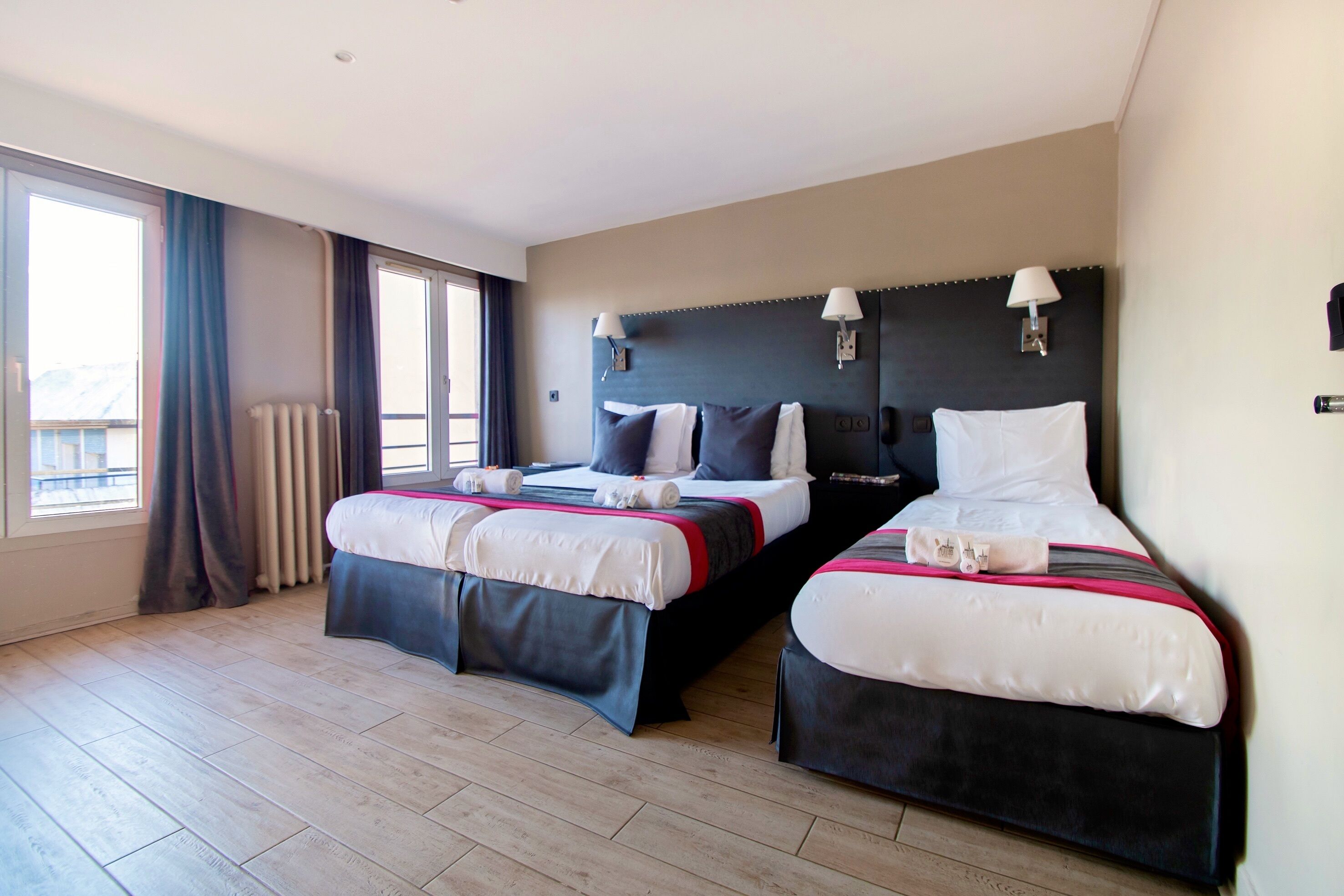 Een hotelkamer met twee bedden, een groot raam en uitzicht op de stad.