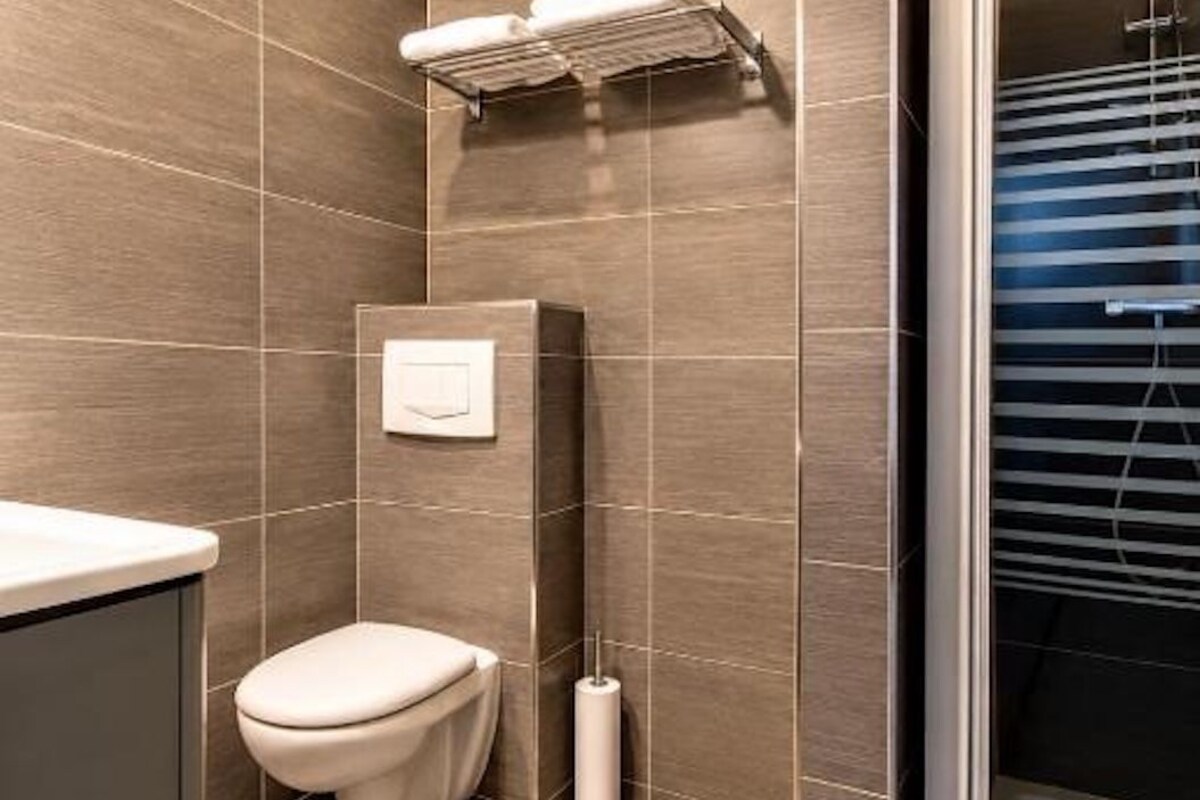 A modern bathroom with a toilet, a towel rack, and a shower area.