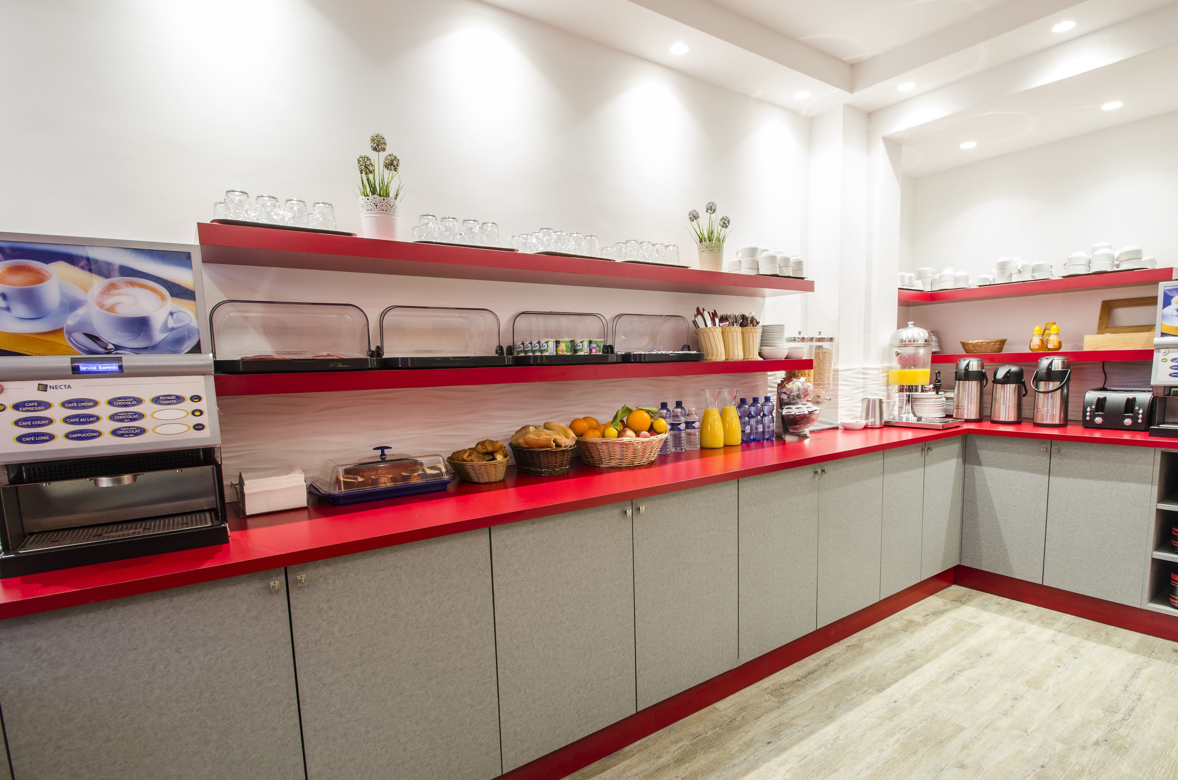A modern kitchen with a red countertop, a coffee machine, and various food items.
