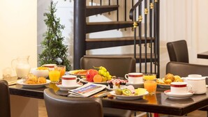 A breakfast setup with various dishes, drinks, and a newspaper on a table. - Hotel Impérial Paris (Paris)