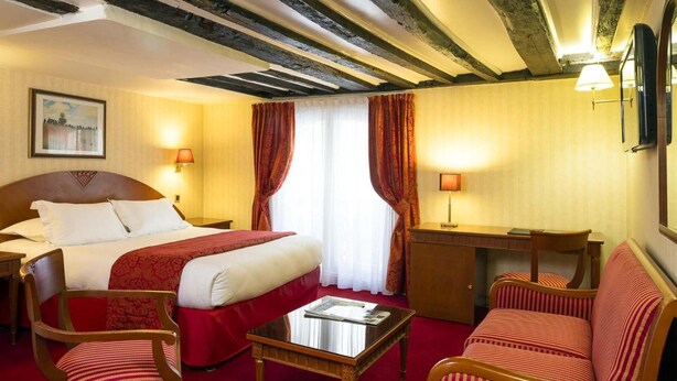 A hotel room with a large bed, two bedside lamps, a desk, a chair, and a sofa. - Hotel Impérial Paris (Paris)