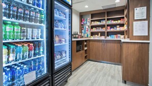 A vending machine with various beverages and a shelf stocked with snacks and other items. - City Express by Marriott Duluth (Duluth)