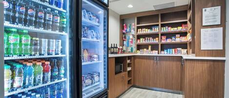 Una máquina expendedora con diversas bebidas y un estante repleto de aperitivos y otros productos.
