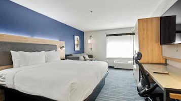 Una habitación de hotel con una cama grande, un escritorio, una silla, un televisor y una ventana.