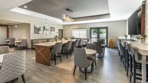 A modern dining area with a central island, multiple seating options, and a large window providing natural light. - City Express by Marriott Duluth (Duluth)