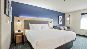 A hotel room with a large bed, a wooden headboard, a nightstand, a desk, a chair, and a window. - City Express by Marriott Duluth (Duluth)