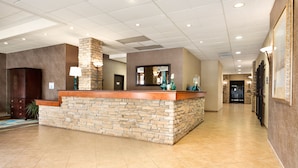 A reception area with a stone counter, a mirror, and a hallway leading to a door. - Wyndham Garden Wichita Downtown (Wichita)