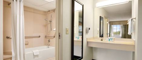Une salle de bain d’hôtel avec une baignoire, une douche et un grand miroir.