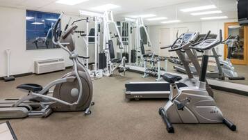 Une salle de sport équipée de divers appareils d’exercice, notamment des tapis de course et des vélos elliptiques, disposés dans un espace vaste et bien aménagé.
