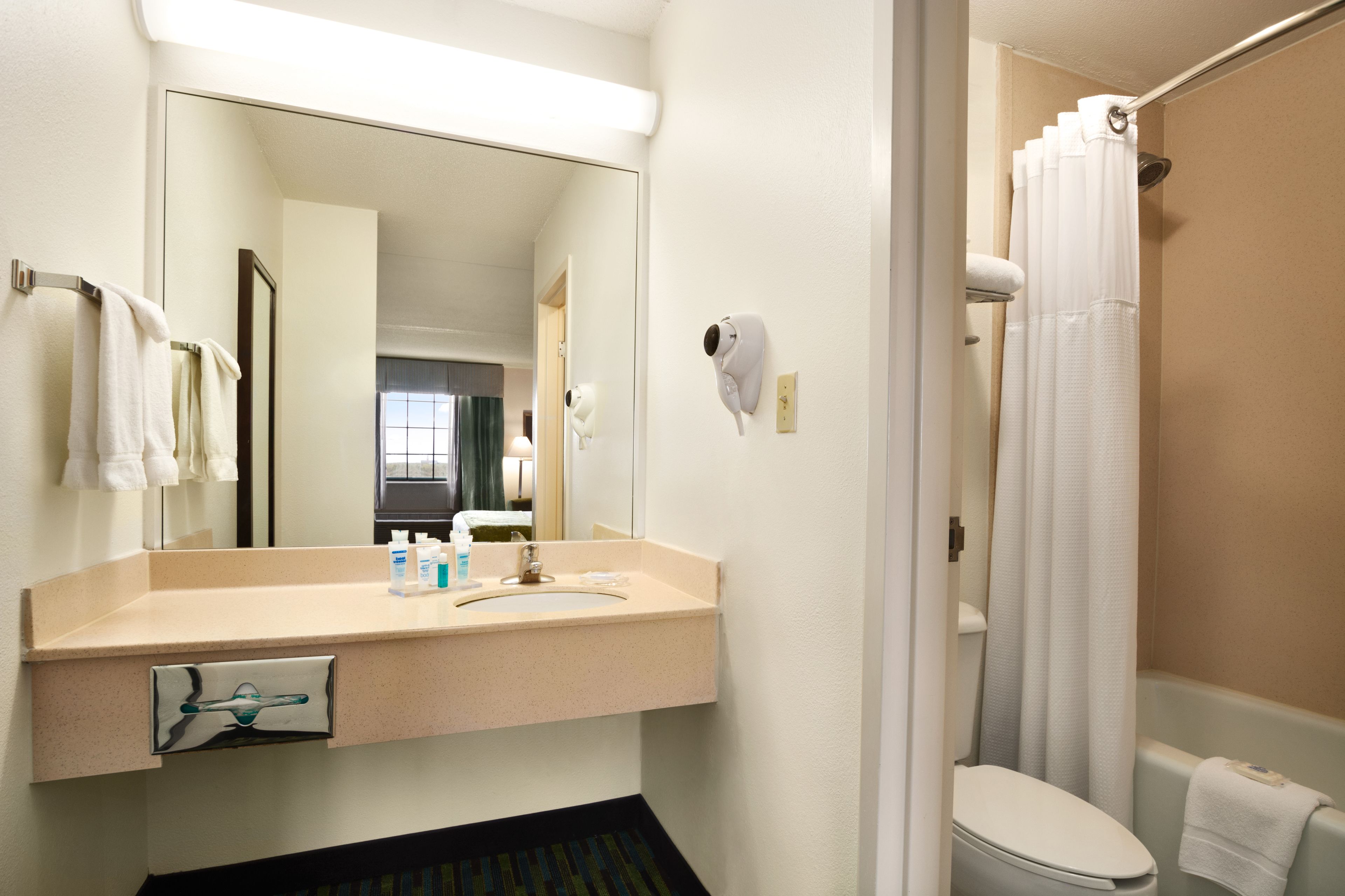 A bathroom with a sink, mirror, towel rack, and a shower curtain.