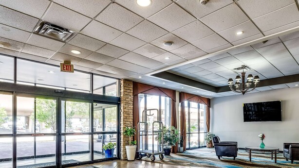 A hotel lobby with large windows, a reception desk, a chandelier, and a cart. - Wyndham Garden Wichita Downtown (Wichita)