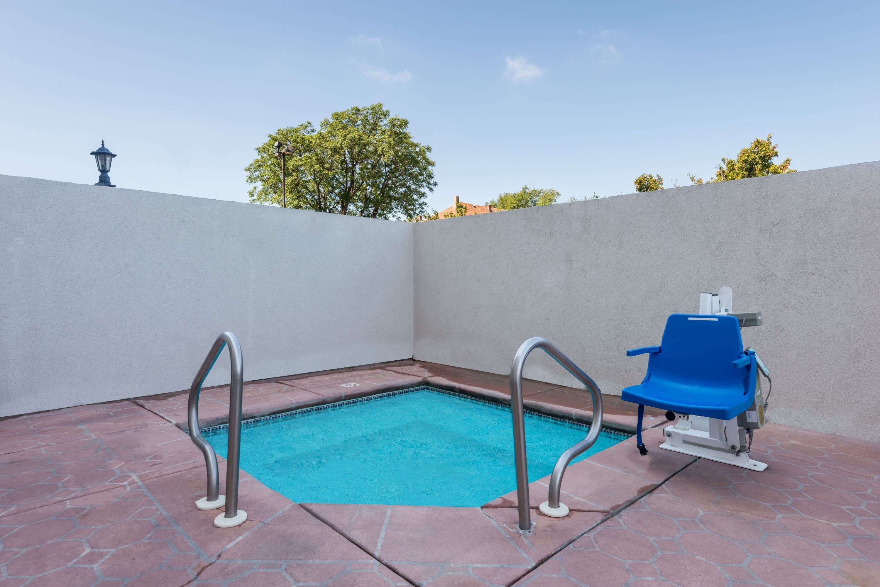 Une piscine avec un élément décoratif aquatique bleu, un fauteuil de jardin bleu et un lampadaire en arrière-plan.