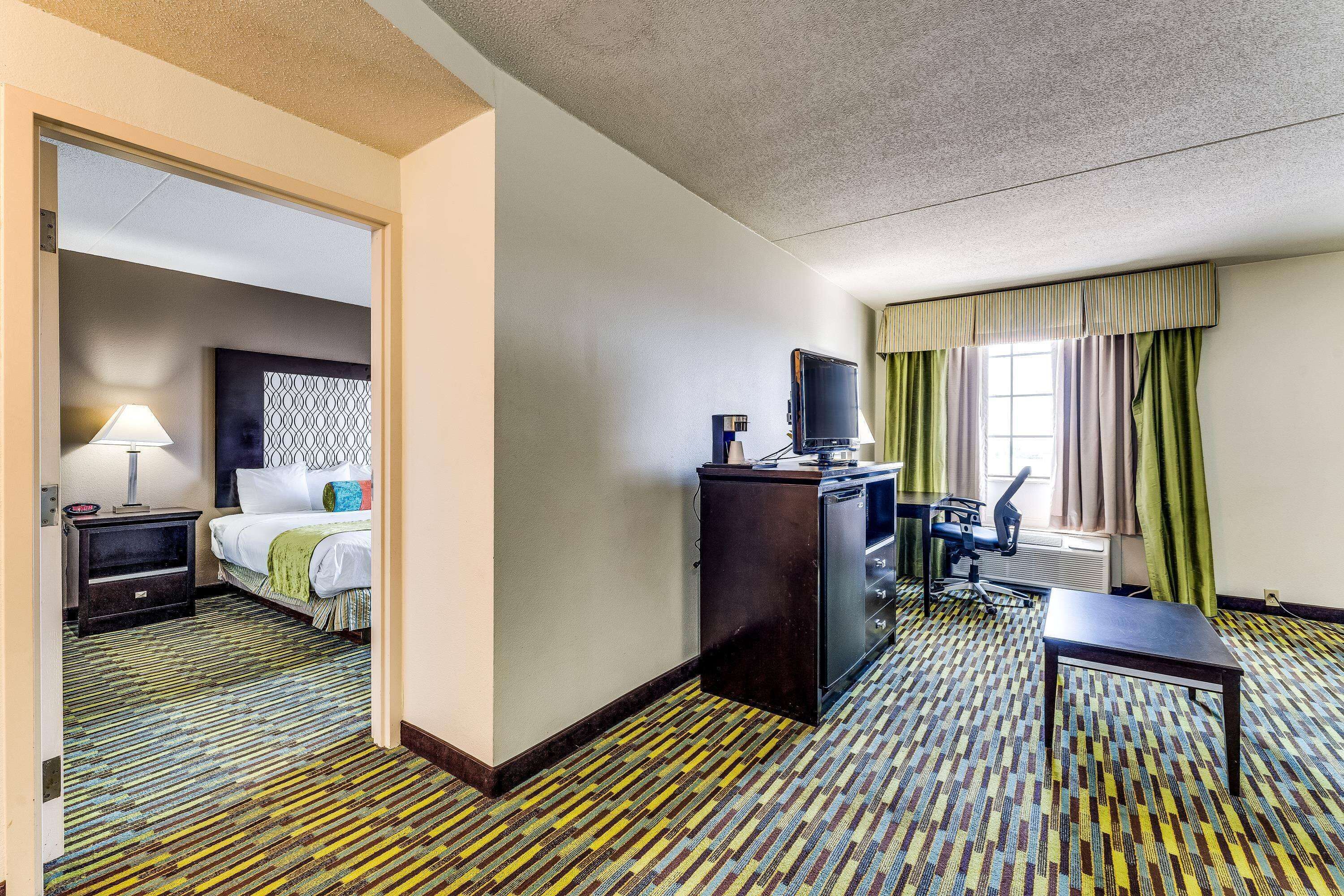 A hotel room with a bed, desk, chair, and a television.