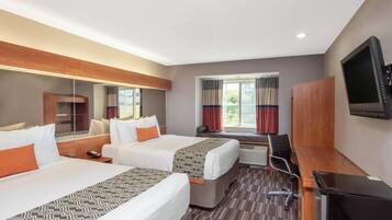 A hotel room with two beds, a desk, a flat-screen TV, and a window with curtains.