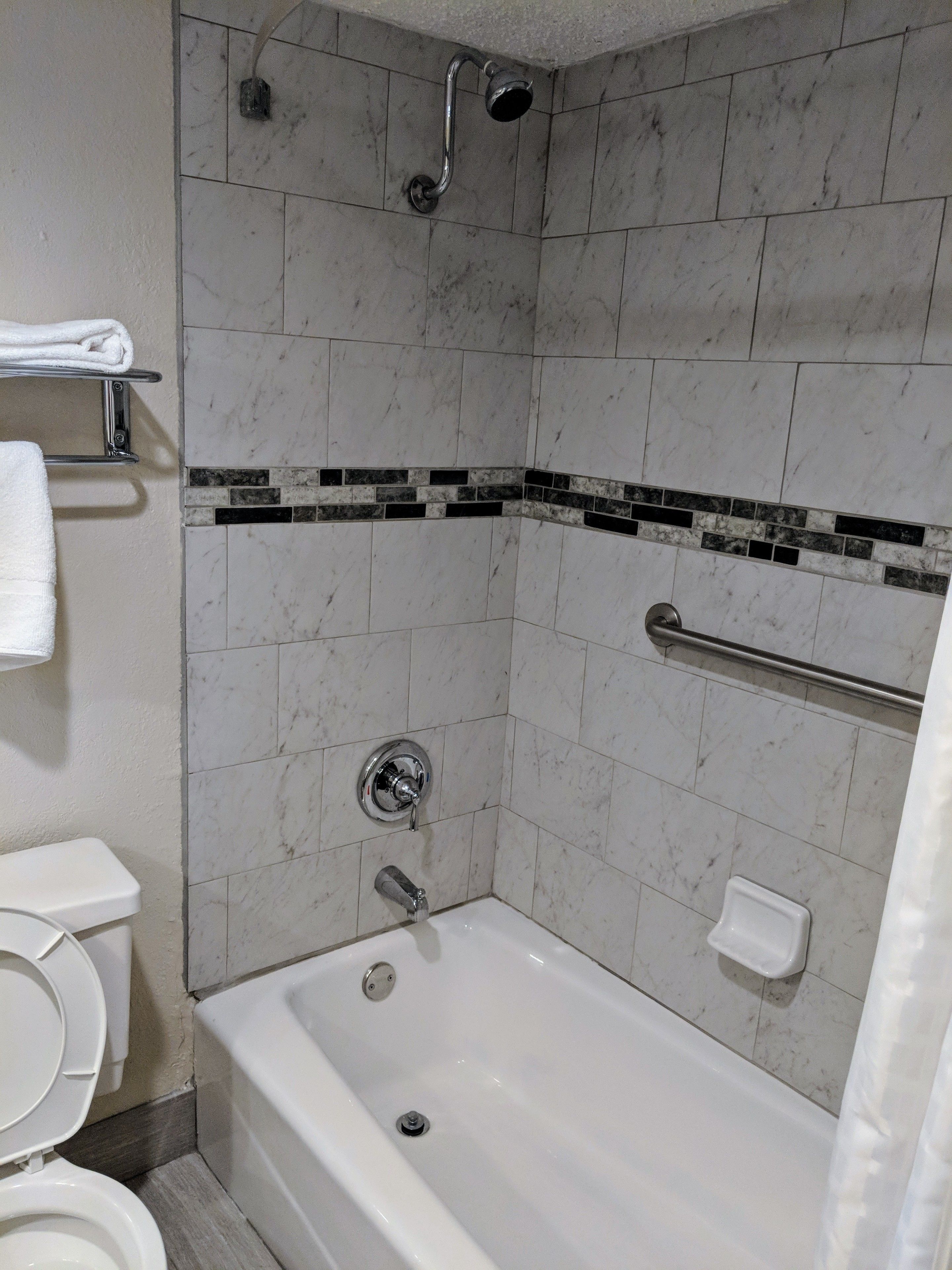 Et badeværelse med badekar, toilet, brusebad og et håndklædetørrestativ.