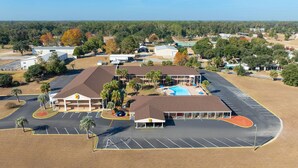 An aerial view of a hotel with a swimming pool, parking lot, and surrounding greenery. - Super 8 by Wyndham Lake City (Lake City)