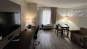 Hotellihuone, jossa on televisio, työpöytä, tuoli ja sohva.