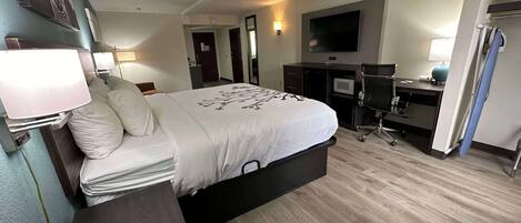 A modern hotel room with a bed, desk, and flat-screen TV.