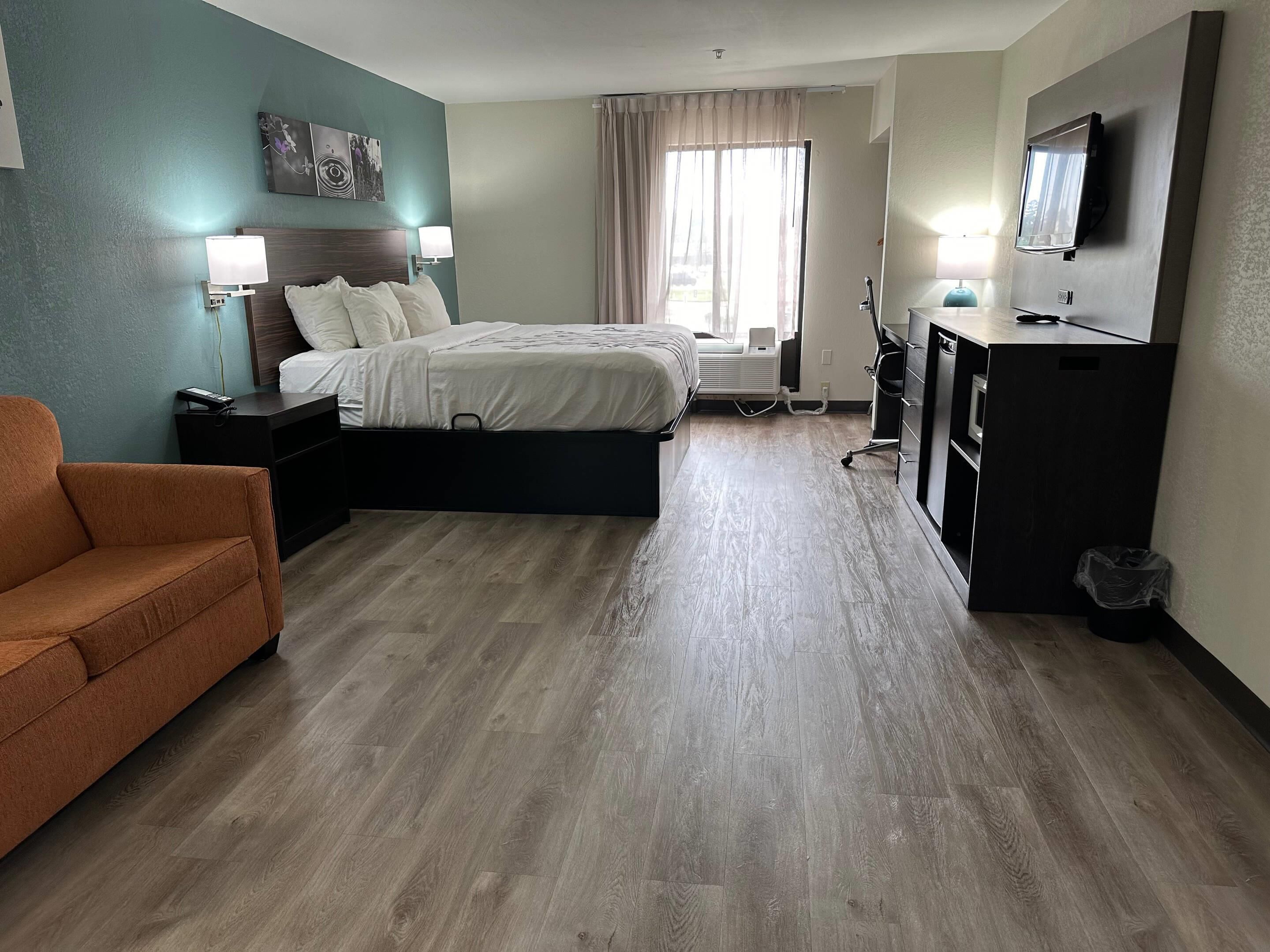 A hotel room with a bed, a desk, a TV, and a chair.
