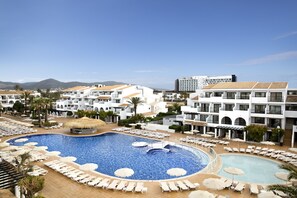 A resort with a large swimming pool surrounded by sun loungers and umbrellas, white buildings, and a clear sky. - FERGUS Style Bahamas (Sant Josep de sa Talaia)