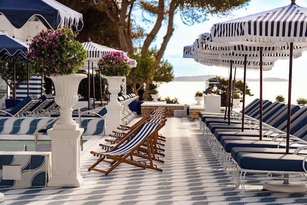 Una piscina al aire libre, sombrillas, sillones reclinables de piscina