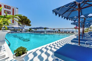 Una piscina al aire libre, sombrillas, tumbonas