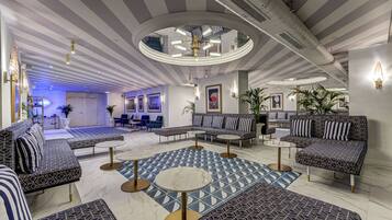 A modern lounge area with striped sofas, round tables, and a central circular ceiling feature.