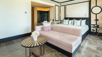 Une chambre d’hôtel moderne avec un grand lit, un canapé, une petite table ronde et un miroir.