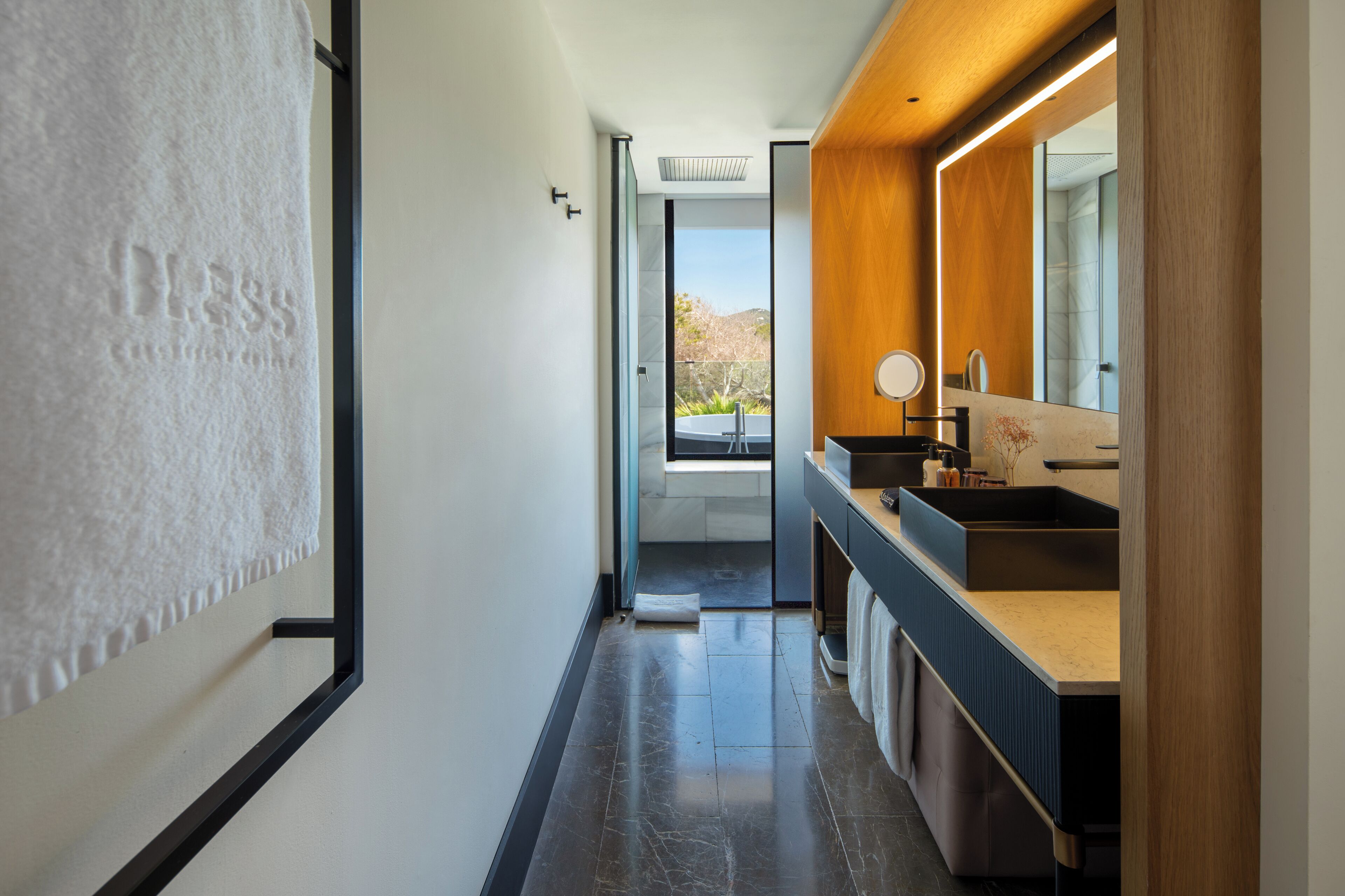 A modern bathroom with a large mirror, a sink, and a view of a balcony.