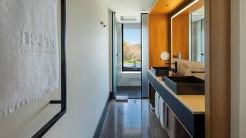 A modern bathroom with a large mirror, a sink, and a view of a balcony.