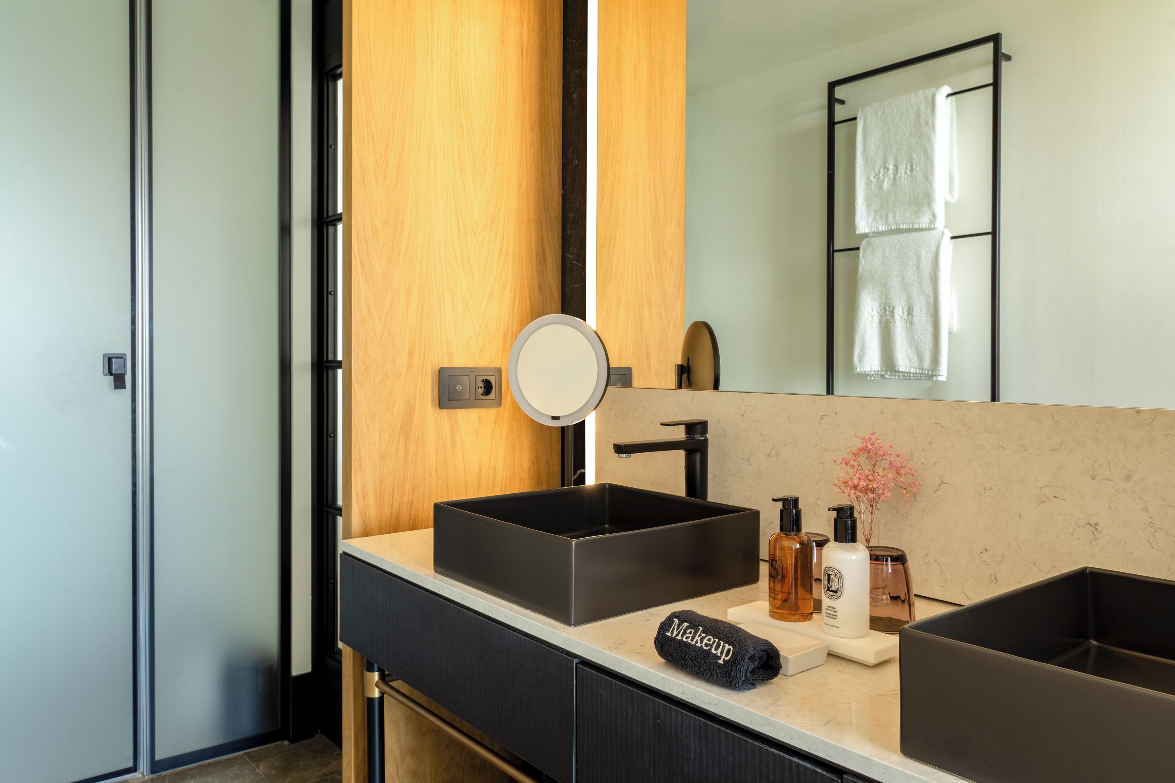 A modern bathroom with a large mirror, two sinks, and a vanity with storage drawers.