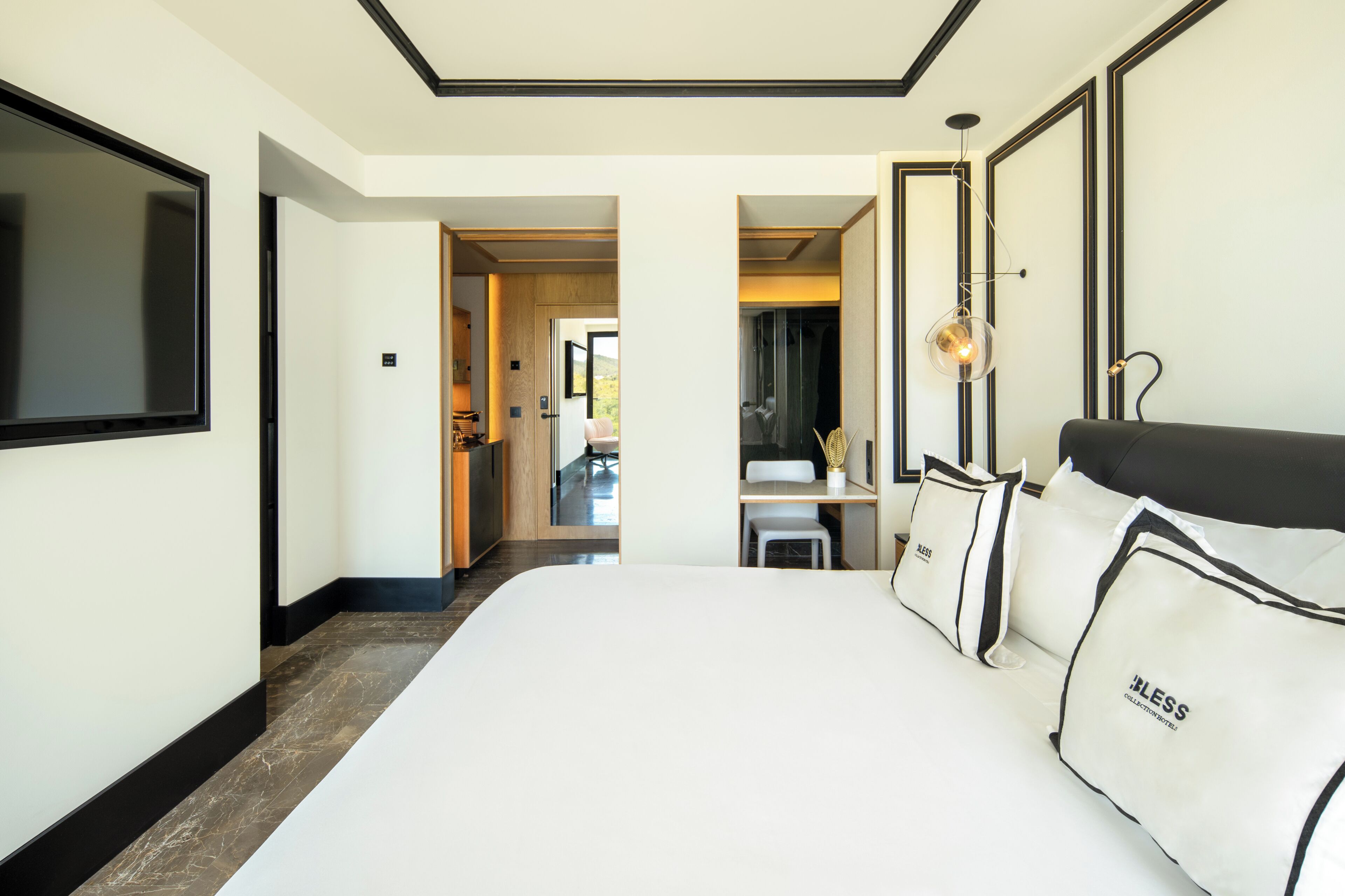A hotel room with a large bed, a TV, and a desk with a chair.