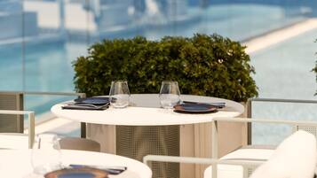 A round table with a white tablecloth, two glasses, and a plate set for two.