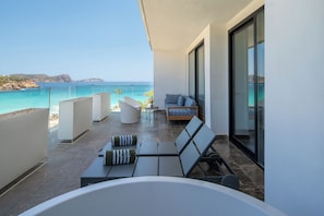 Ein Balkon mit Meerblick, eine Sitzecke mit Kissen und eine Badewanne.