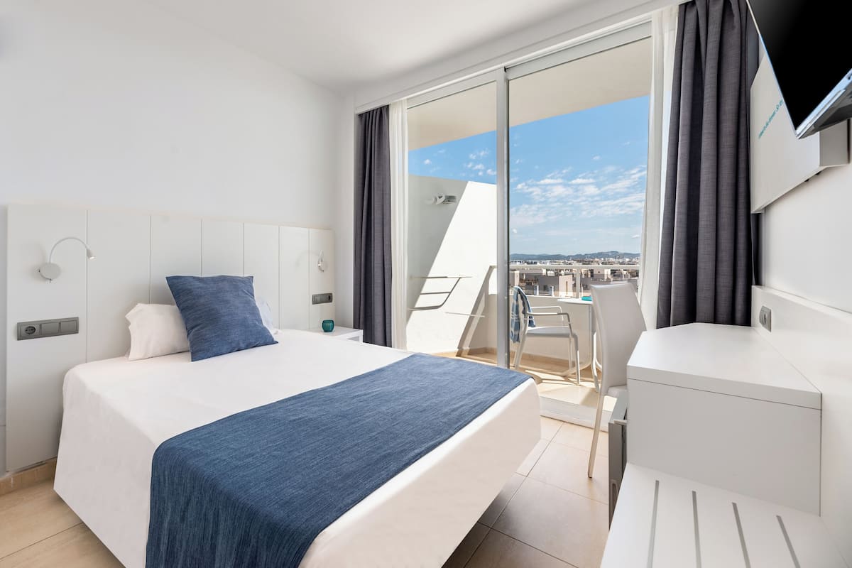 Ein modernes Hotelzimmer mit Bett, Schreibtisch und Blick auf die Stadt.