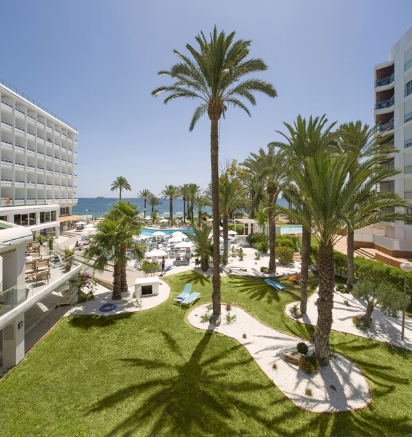 Un resort con zona de piscina, palmeras y vistas al mar.