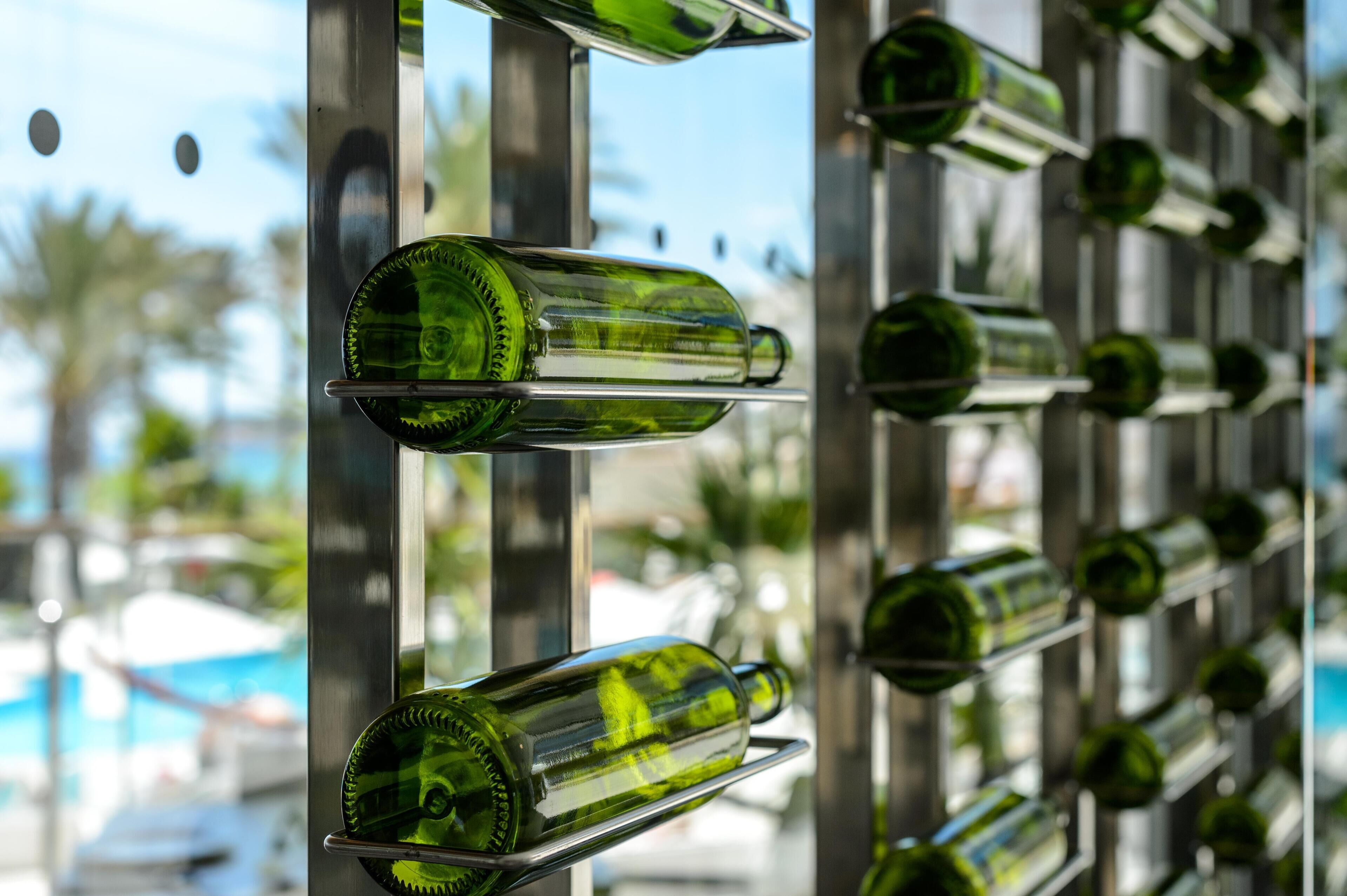 A wall of empty green glass bottles arranged in a grid pattern.