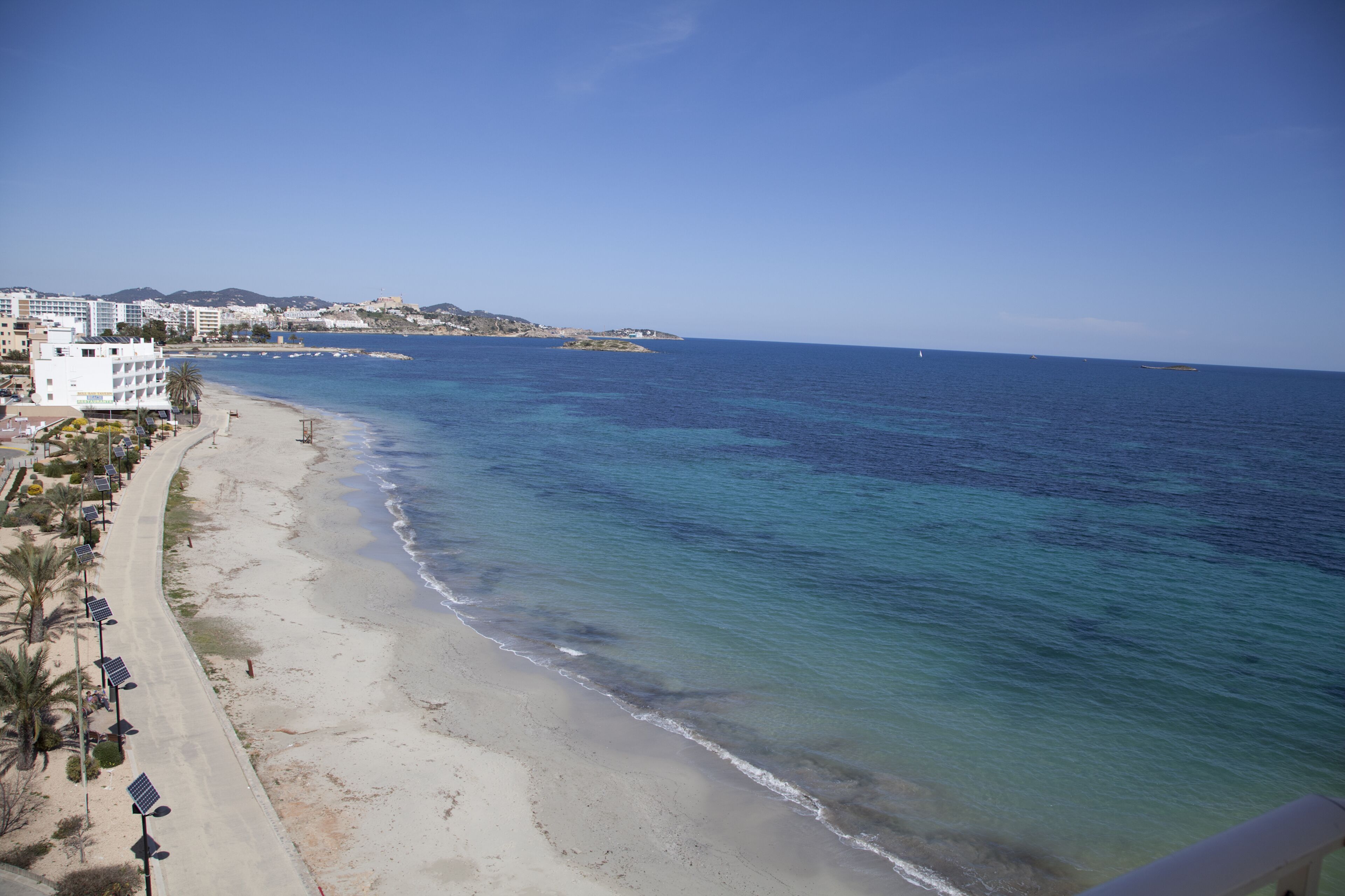 Una playa con vista clara al océano y una hilera de edificios a lo largo de la orilla.