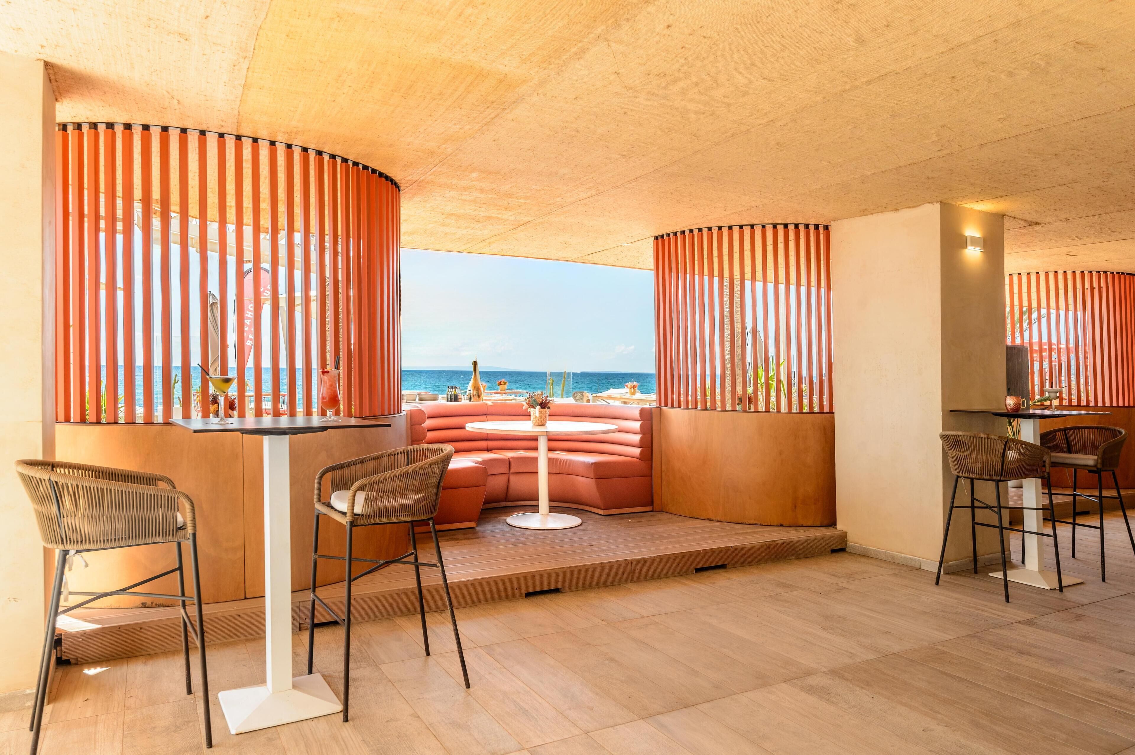 A modern lounge with a curved seating area, a round table, and a view of the sea.