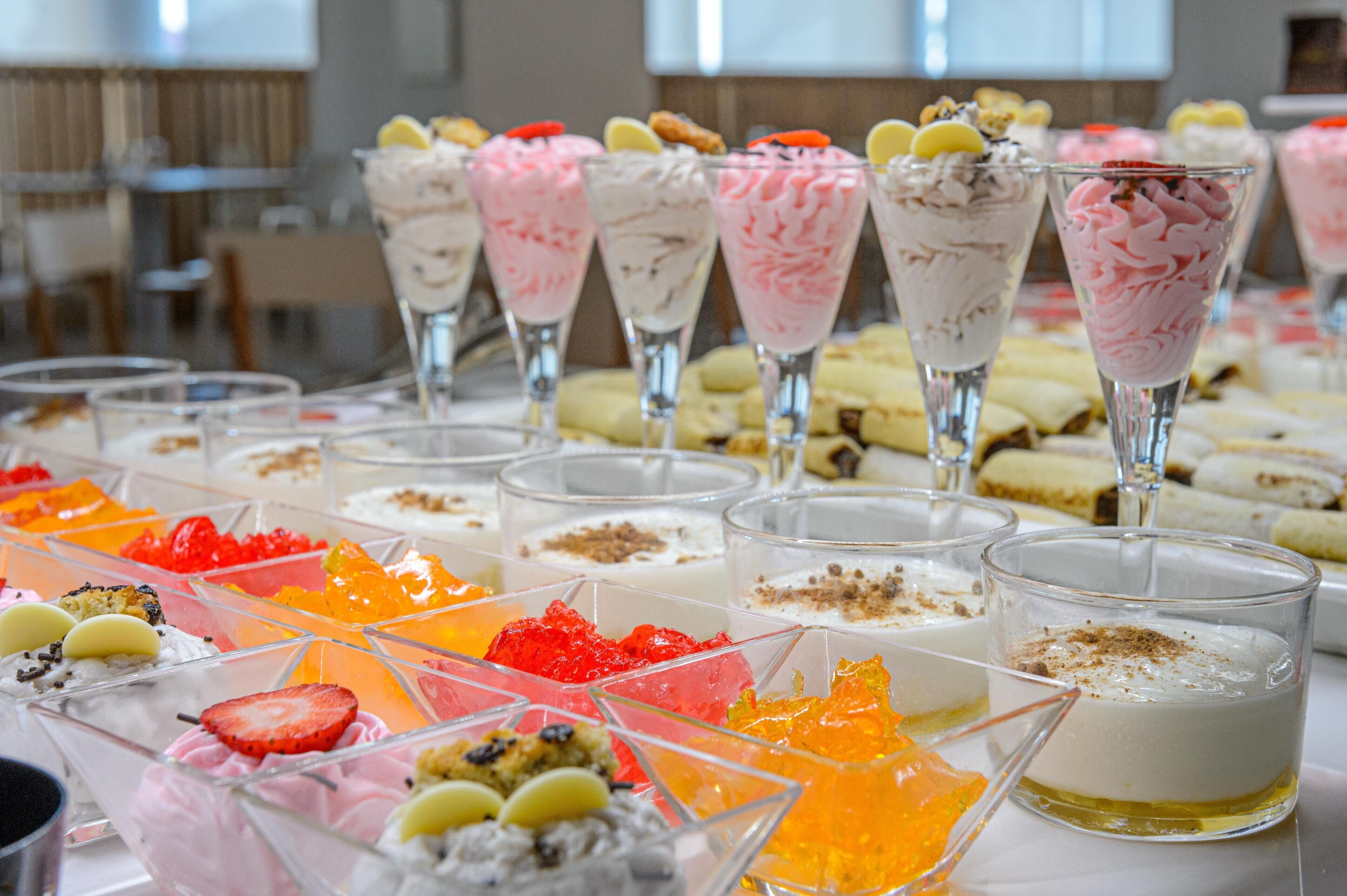A variety of desserts arranged on a table, including parfaits and fruit tarts.
