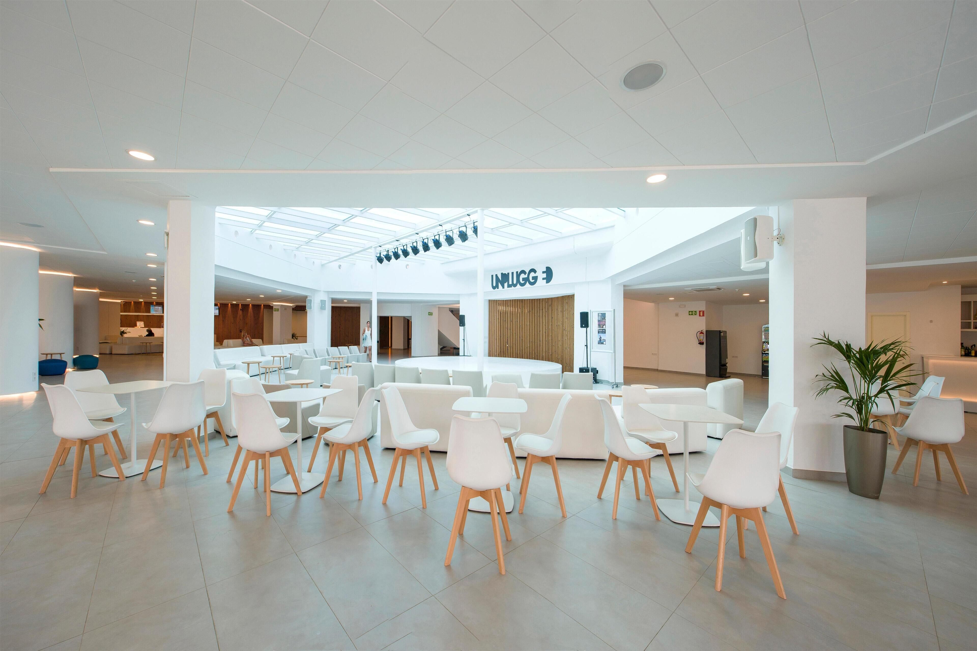 Ein großzügiger, moderner Lounge-Bereich mit weißen Möbeln und einer zentralen Sitzgruppe.