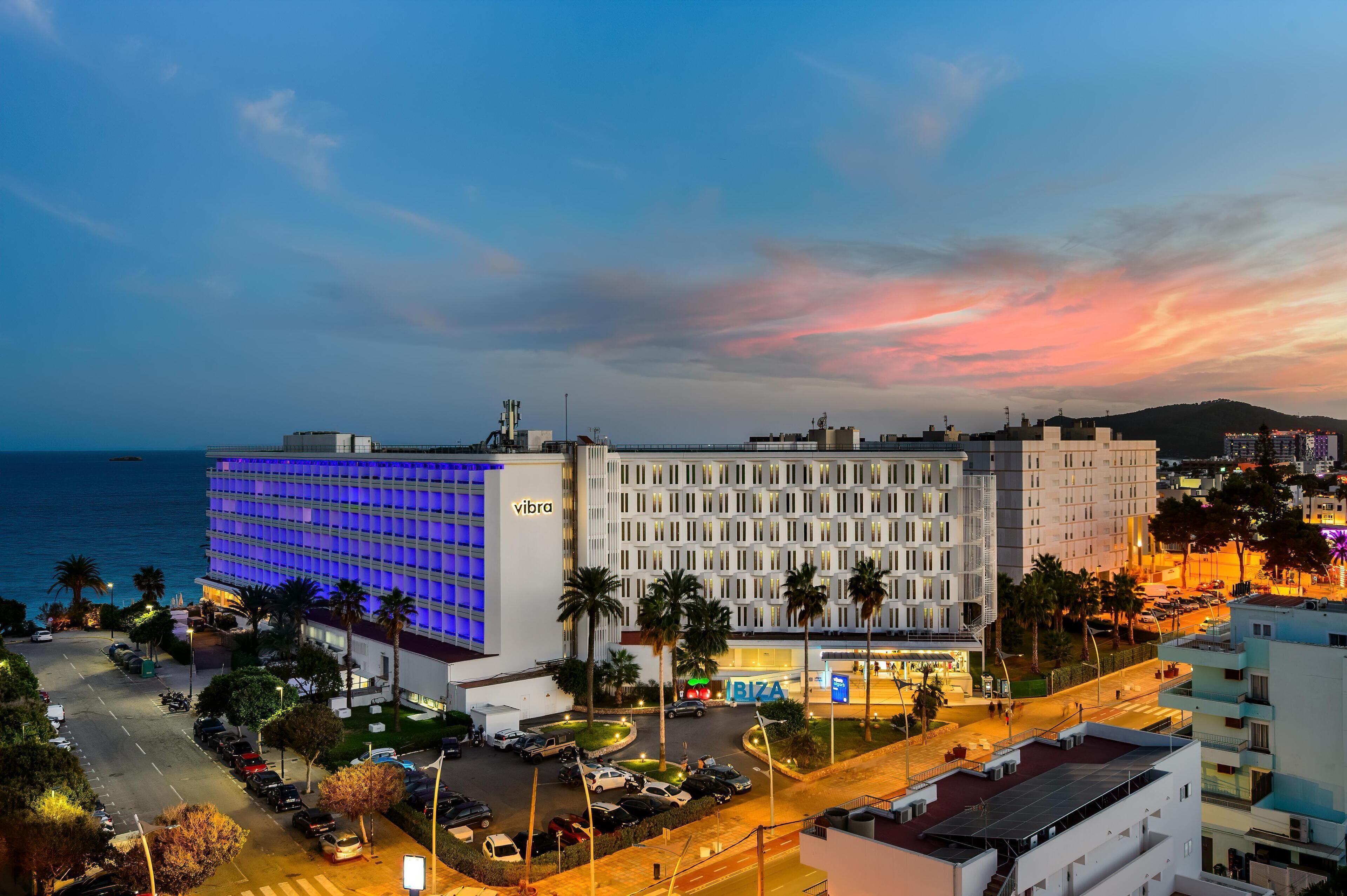 A hotel with a modern design, a parking lot, and a view of the sea.