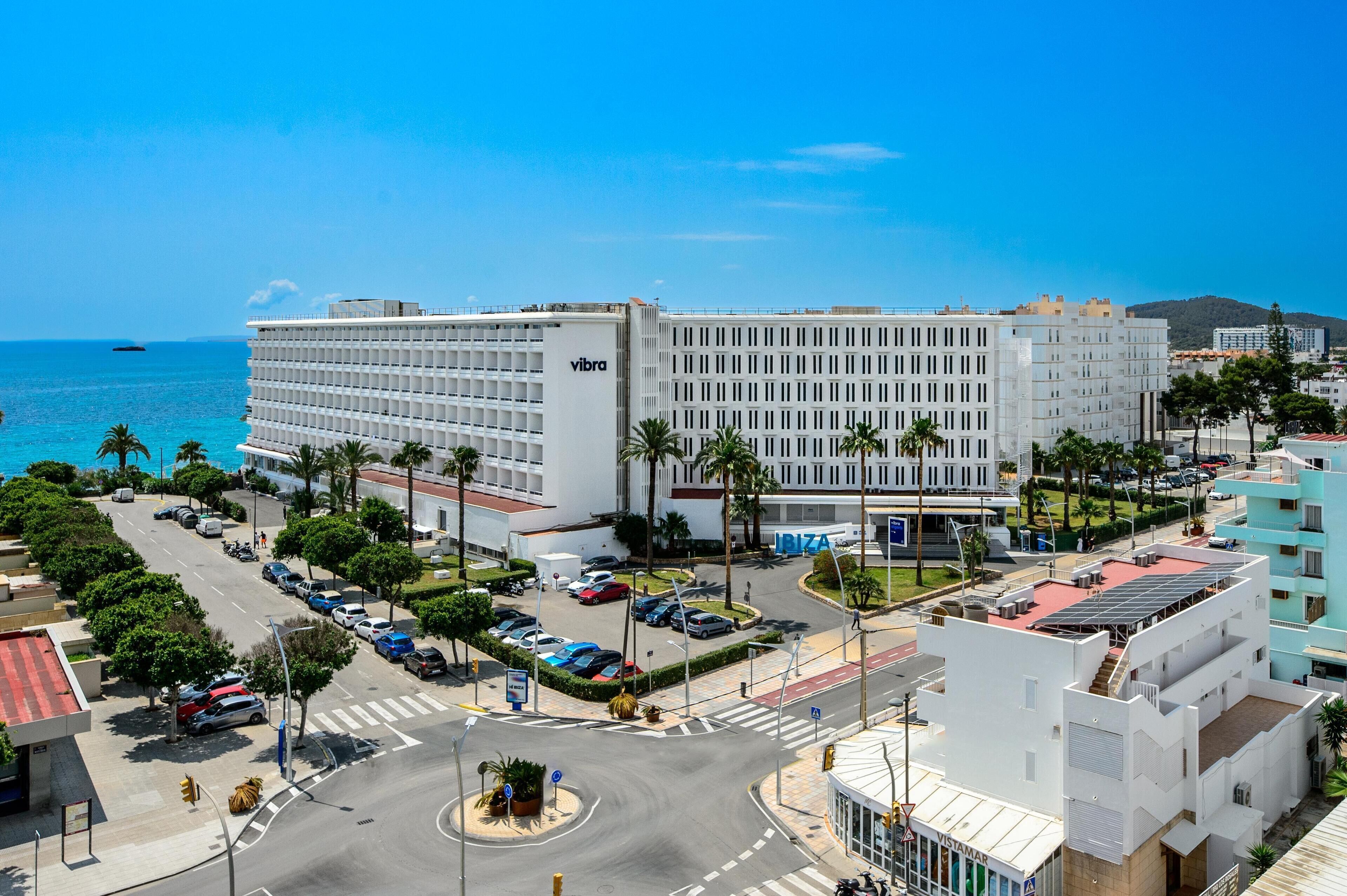 Een modern hotel met een centrale binnenplaats, een parkeerplaats en uitzicht op zee.