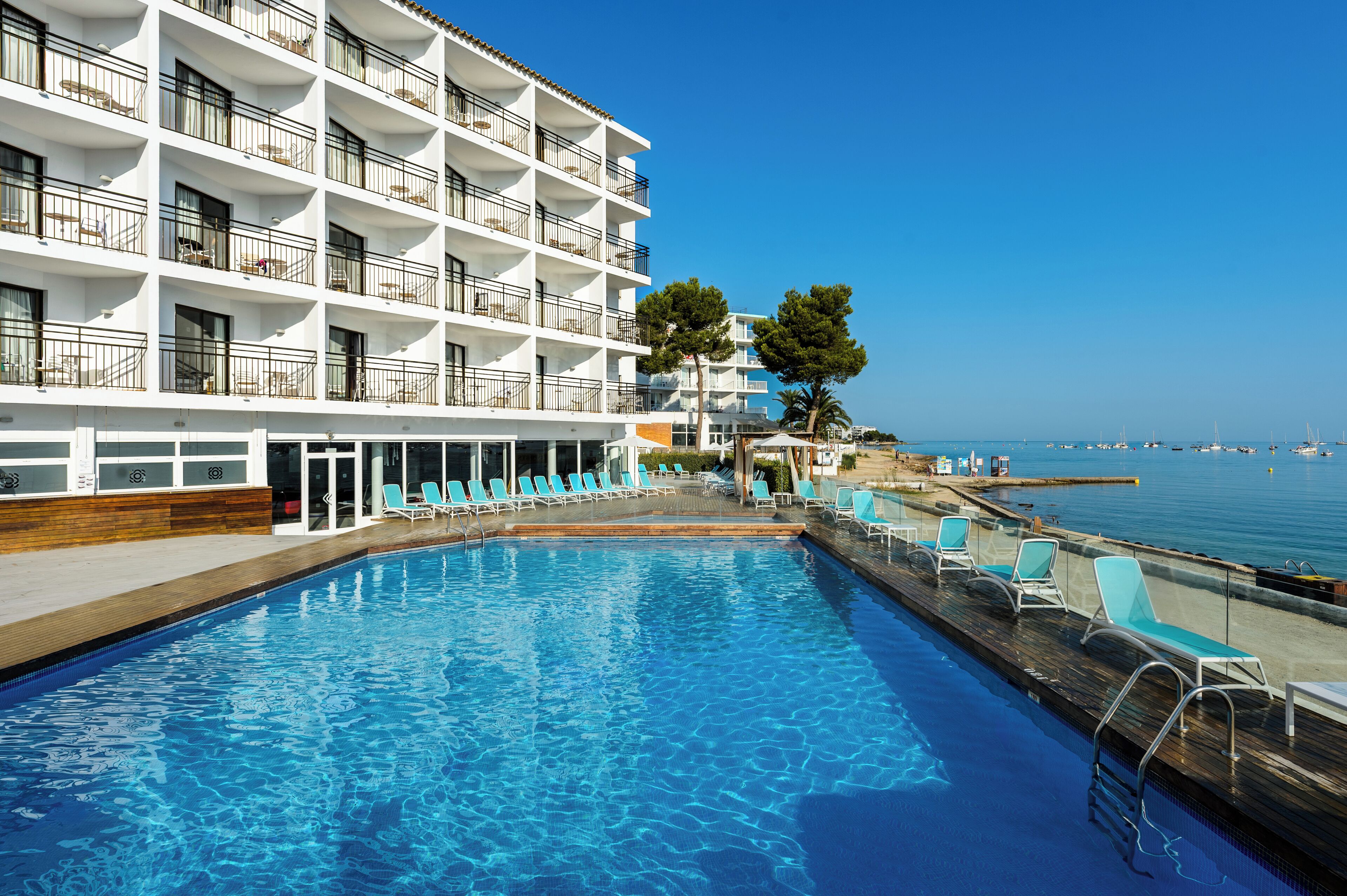 A hotel with a pool, balconies, and a view of the sea.
