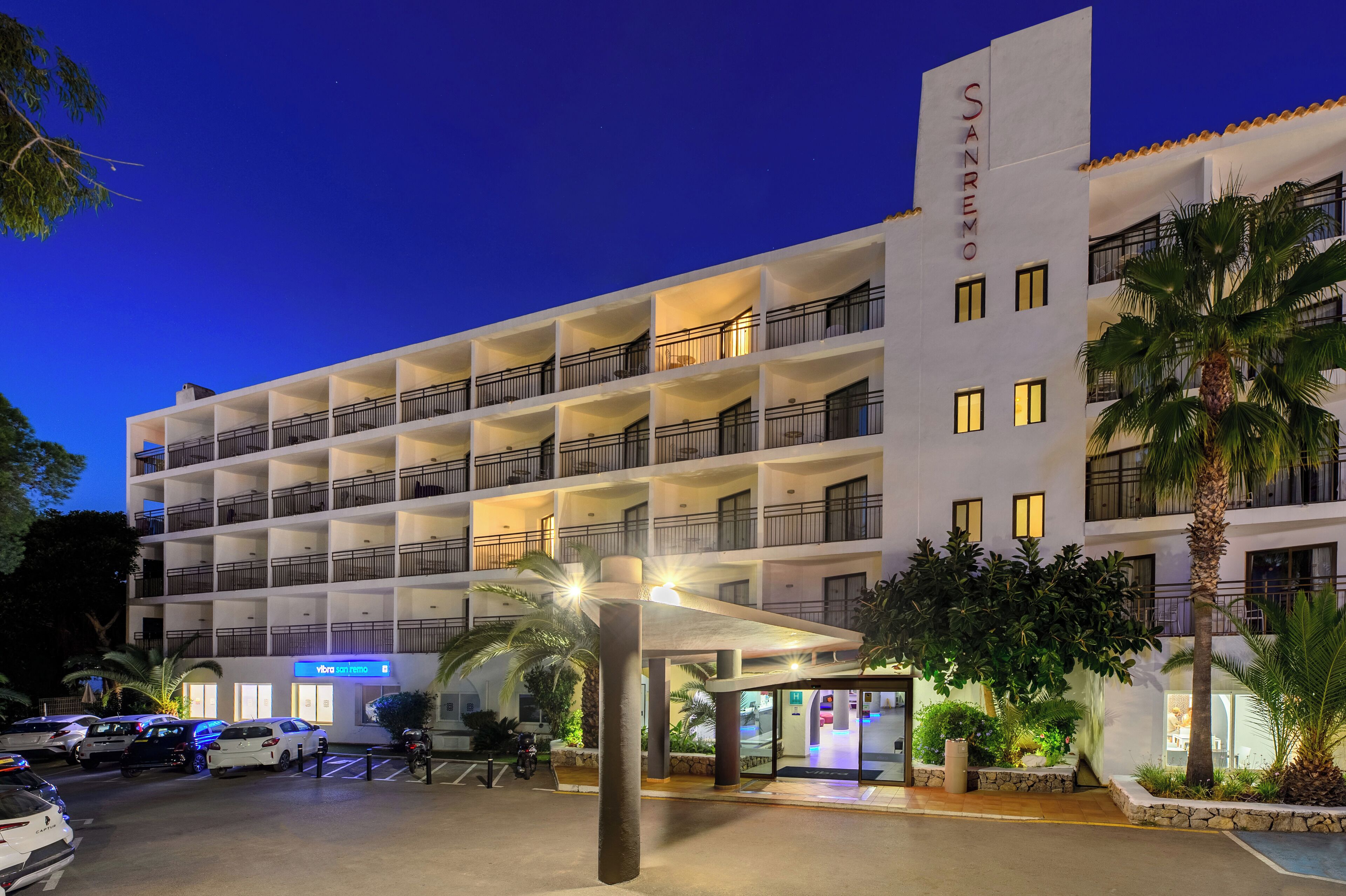 A multi-story hotel with balconies, a parking area, and a sign indicating a spa.